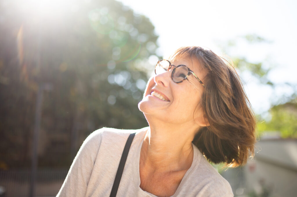 senhora de 60 anos sorridente com óculos a ilustrar o envelhecimento da visão