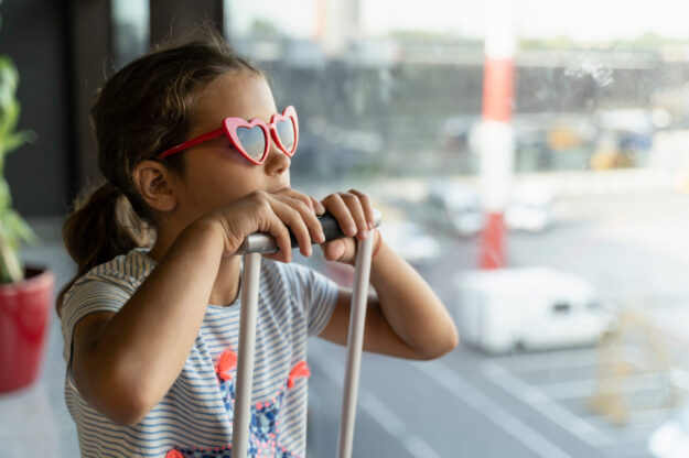 cuidados-visao-em-viagem-clinialba menina com mala de viagem com oculos de sol - cuidados com avisaõ em viagem